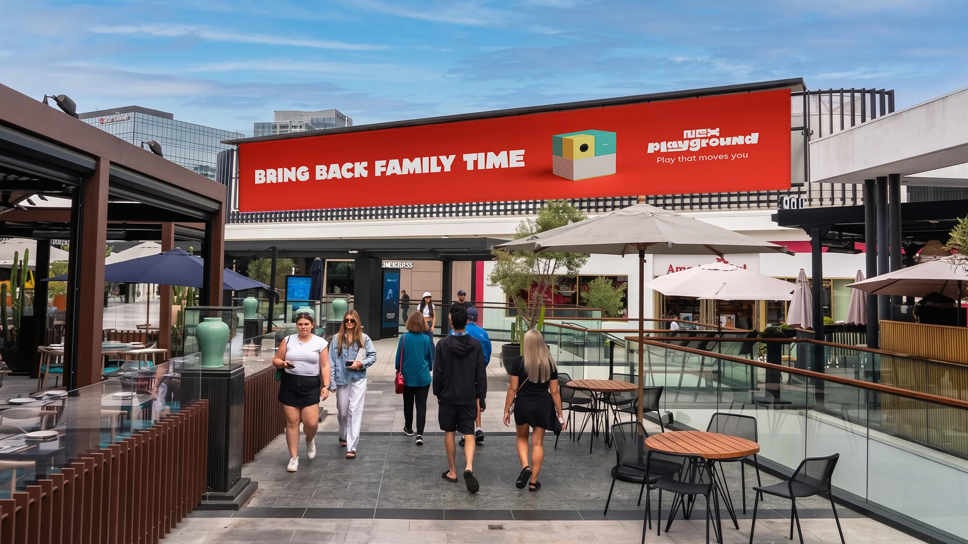 Red Bring Back Family Time billboard above a Los Angeles shopping walkway — campaign placement mockup