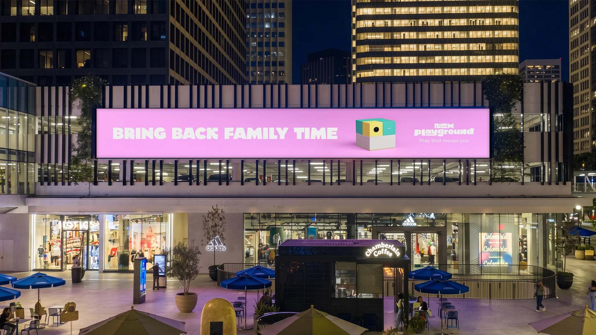 Pink Bring Back Family Time billboard above a Los Angeles shopping plaza at night — campaign placement visual